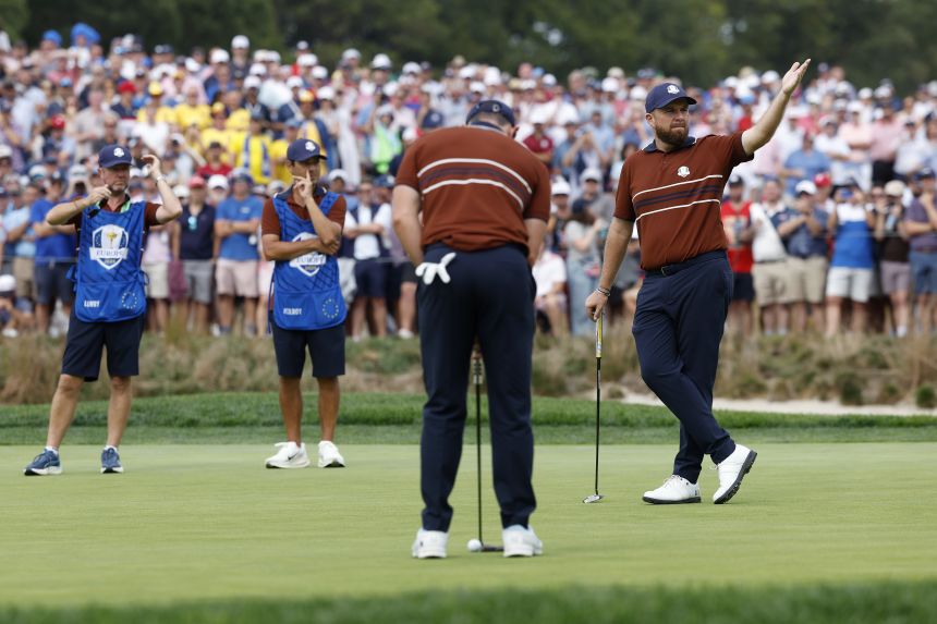 Team Europe's Shane Lowry reacts to the crowd as teammate Rory McIlroy looks to putt on the sixth hole during the Saturday afternoon four-ball matches of the 2025 Ryder Cup.