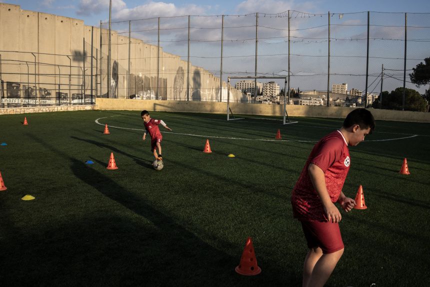 Displaced Palestinian youths take part in a training session at the Aida Refugee Camp's soccer pitch, next to the separation wall outside Bethlehem in the occupied West Bank, on December 16, 2025, a few weeks after an Israeli military decision to demolish the field.