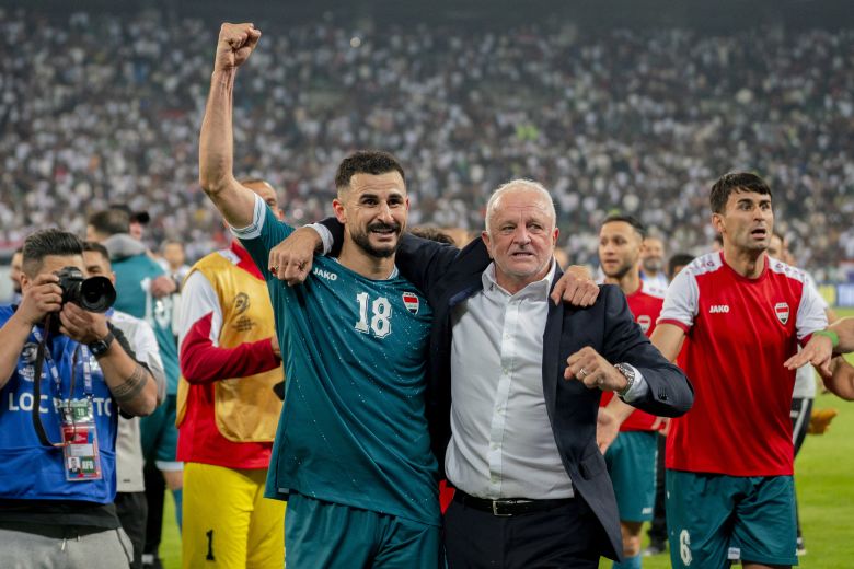 Iraq's Aymen Hussein raises his fist alongside head coach Graham Arnold as they celebrate getting past the UAE in November.