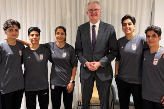 Australia's Minister for Home Affairs Tony Burke (center) poses with five Iranian women soccer players who have been granted asylum in Australia. (Australia Ministry of Home Affairs via AP)