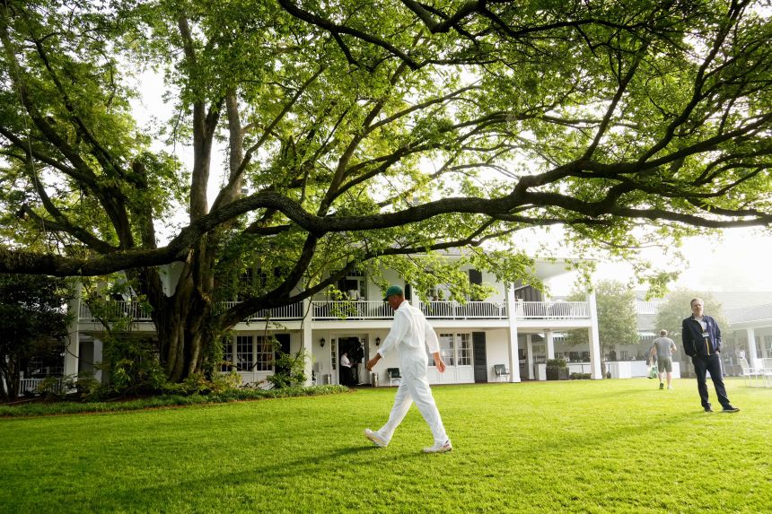 Caddie Jim "Bones" Mackay walks under the big oak tree by the Augusta National clubhouse in 2023.