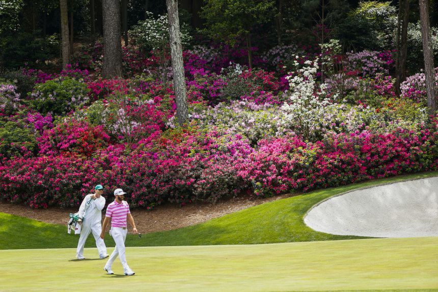 Dustin Johnson and his caddie walk toward the 13th green in 2021.