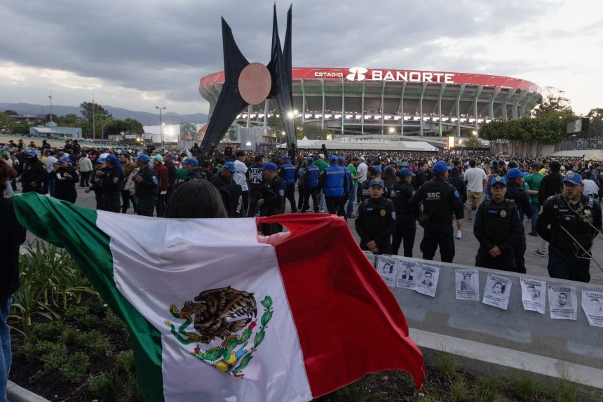 Police officers stand guard near posters of missing people during a protest outside the Estadio Banorte in March.