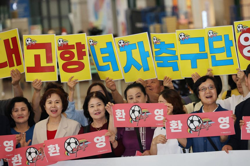 Activists hold signs to welcome members of North Korean soccer club Naegohyang Women’s FC as they arrive Sunday.