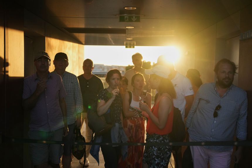 Visitors wait for a break to enter a match at the French Open on May 26.