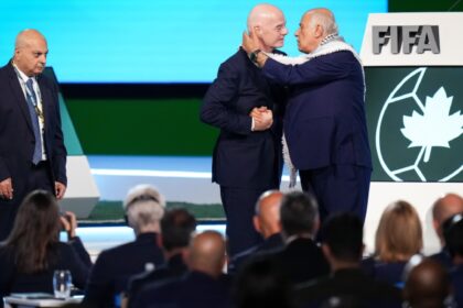 Palestinian Football Association President Jibril Rajoub, right, reaches to kiss FIFA President Gianni Infantino on the cheek after speaking as Israel Football Association Vice-President Basim Sheikh Suliman, left, watches during the 76th FIFA Congress in Vancouver, British Columbia, Thursday, April 30, 2026. (Darryl Dyck/The Canadian Press via AP)