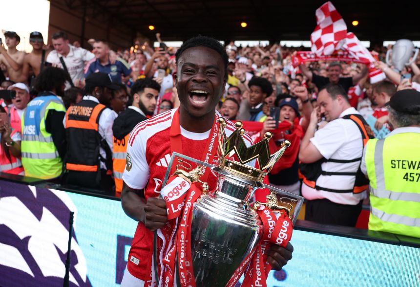 Arsenal's Bukayo Saka celebrates with the Premier League trophy in London on Sunday.