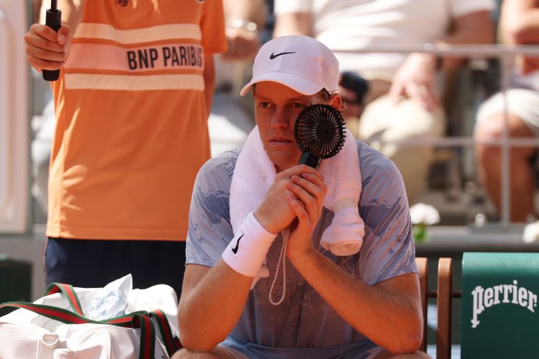 Sinner uses a handheld fan to cool down during a break in play Thursday.