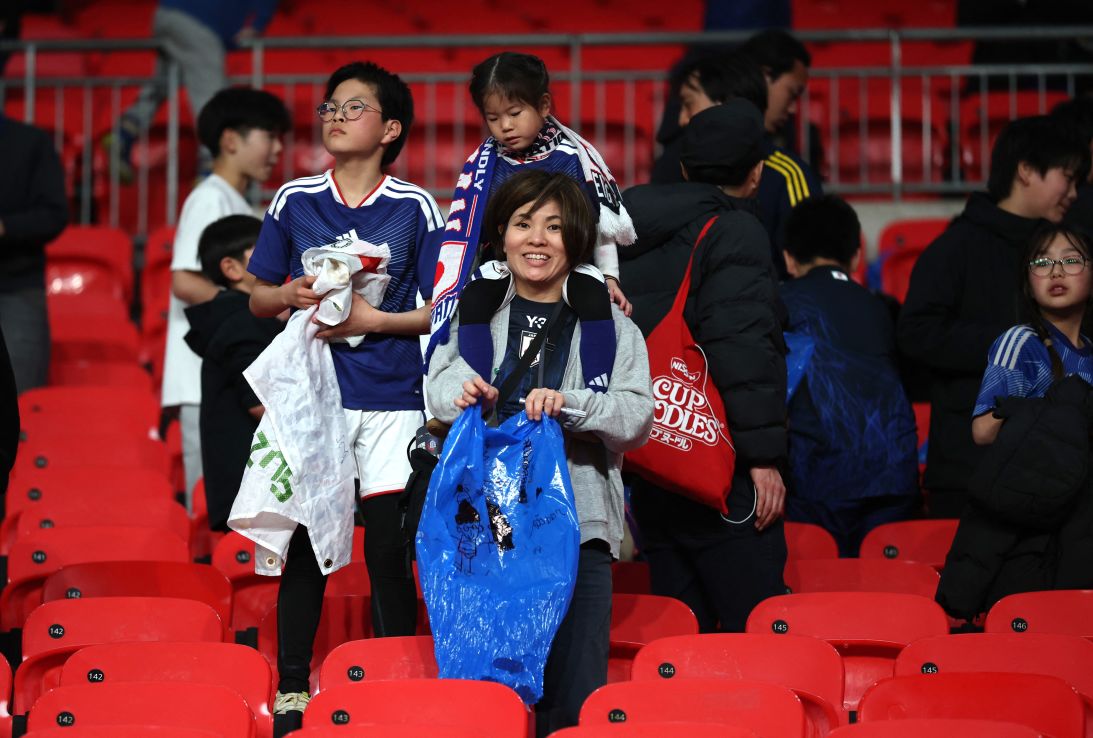 Team Japan's fans clean up trash in the stands after the international friendly against England on March 31 at Wembley Stadium.