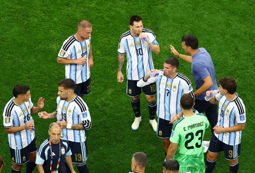 Argentina coach Lionel Scaloni talks to Lionel Messi and Alexis Mac Allister during a hydration break on Monday.