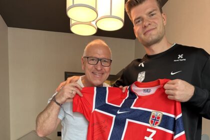 Gøran Sørloth and his son Alexander hold up a Norway shirt together. Alexander is playing for Norway in the World Cup. Gøran played for the national team in 1994.