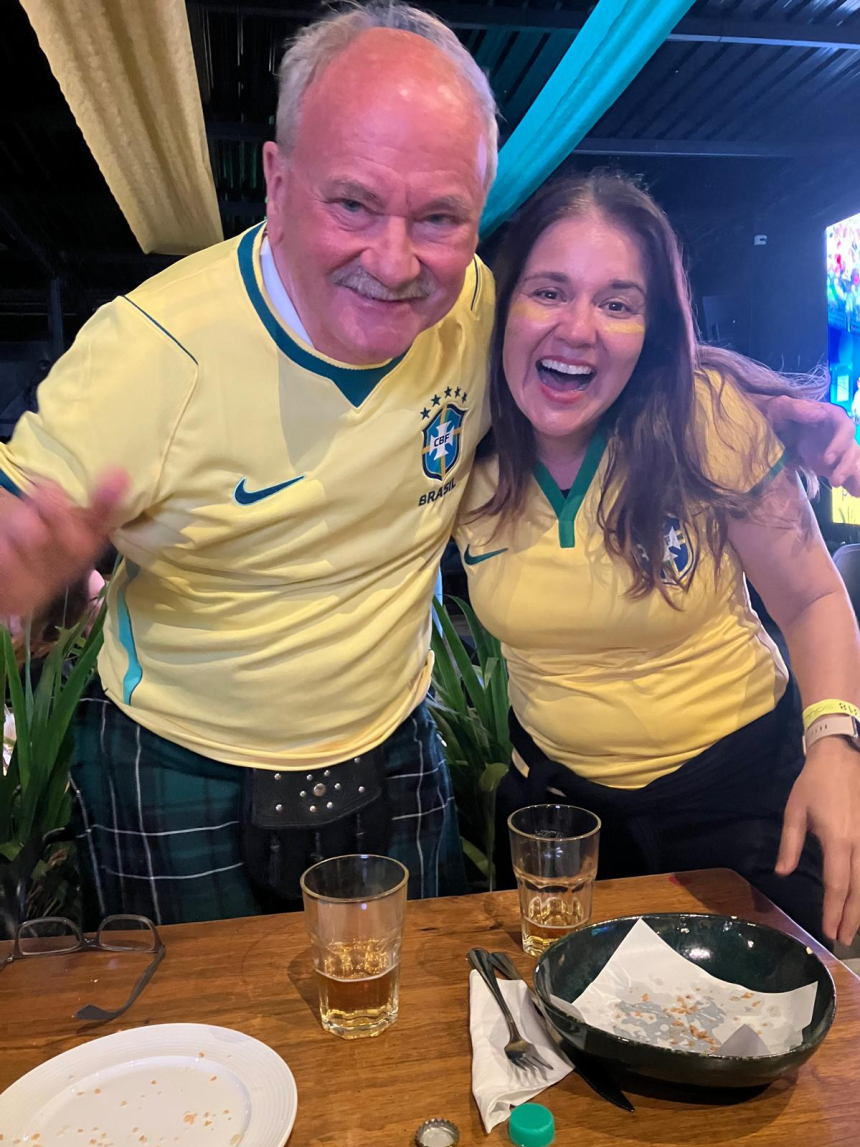 Malcolm McLean wears a Brazil jersey and a Scottish kilt while watching a match at a pub in Brazil.