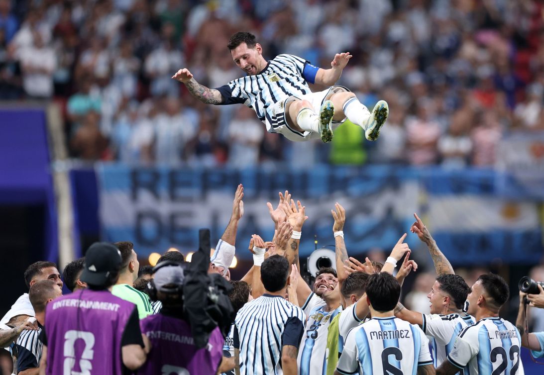 Lionel Messi is thrown into the air by his teammates in celebration.